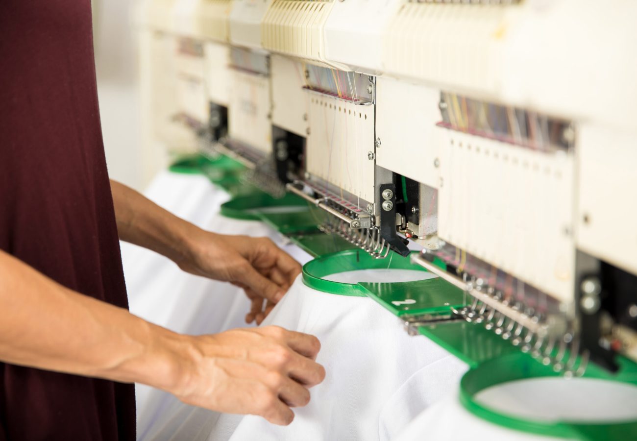 Garments are ready for embroidery Closeup of a woman placing several garments on an embroidery machine in a textile factory